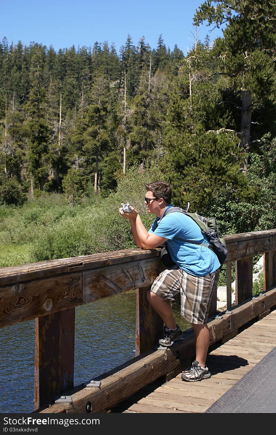 Young teenager standing on a bridge photographing the landscape. Young teenager standing on a bridge photographing the landscape