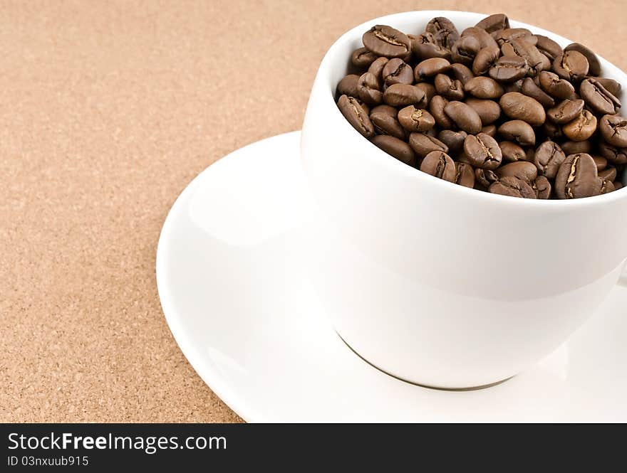 Close coffee cup filled with coffee beans on textured background