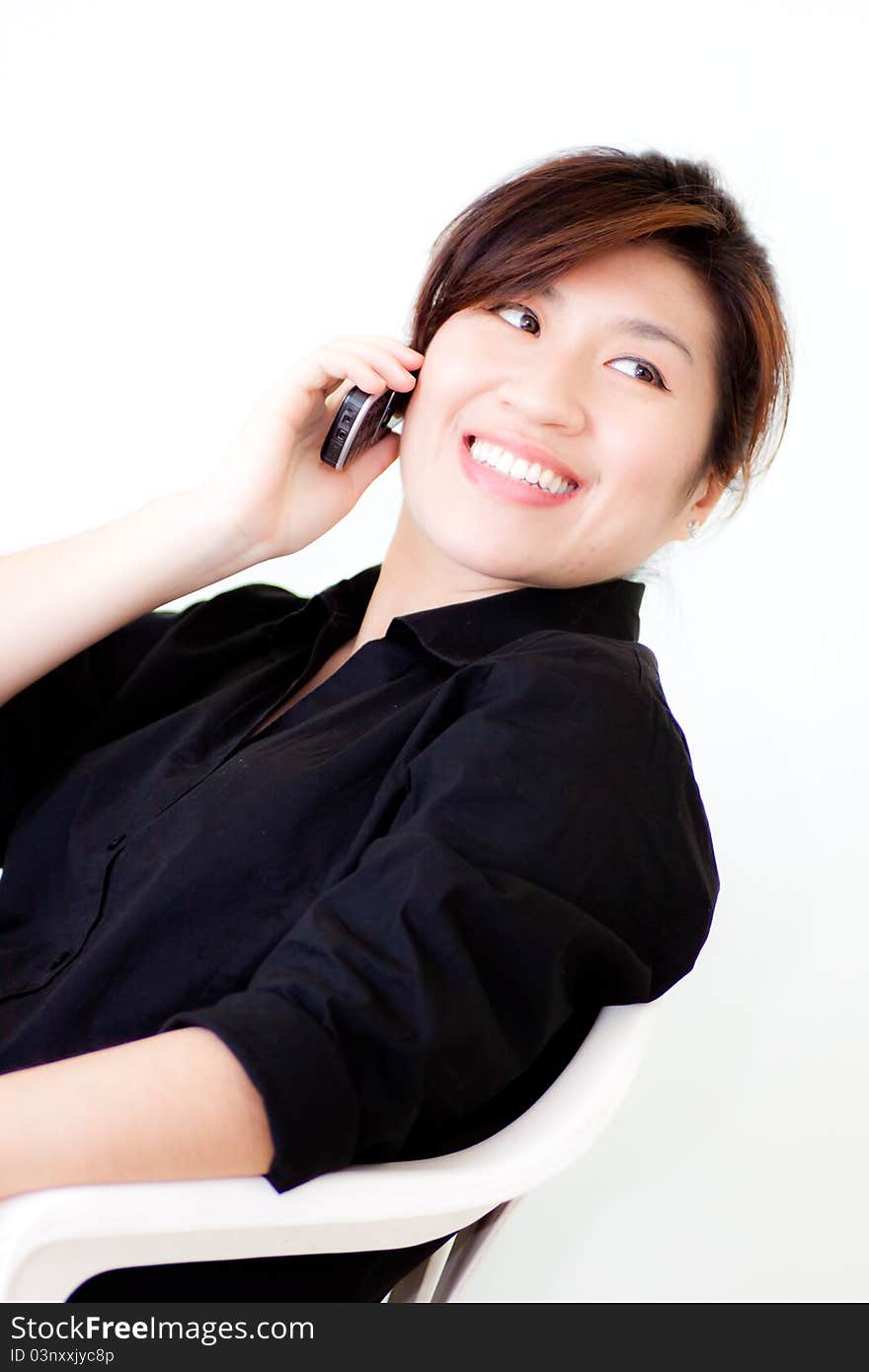 Asian woman in black shirt smiling while telephone on white background. Asian woman in black shirt smiling while telephone on white background