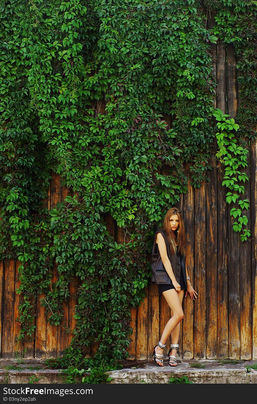 Fashion shot of a beautiful model posing at the vineyard wall