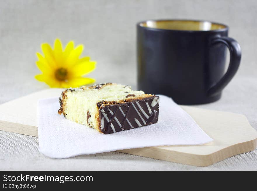 A piece of sliced cake and a cup of coffe. Decorated with yellow flower. A piece of sliced cake and a cup of coffe. Decorated with yellow flower