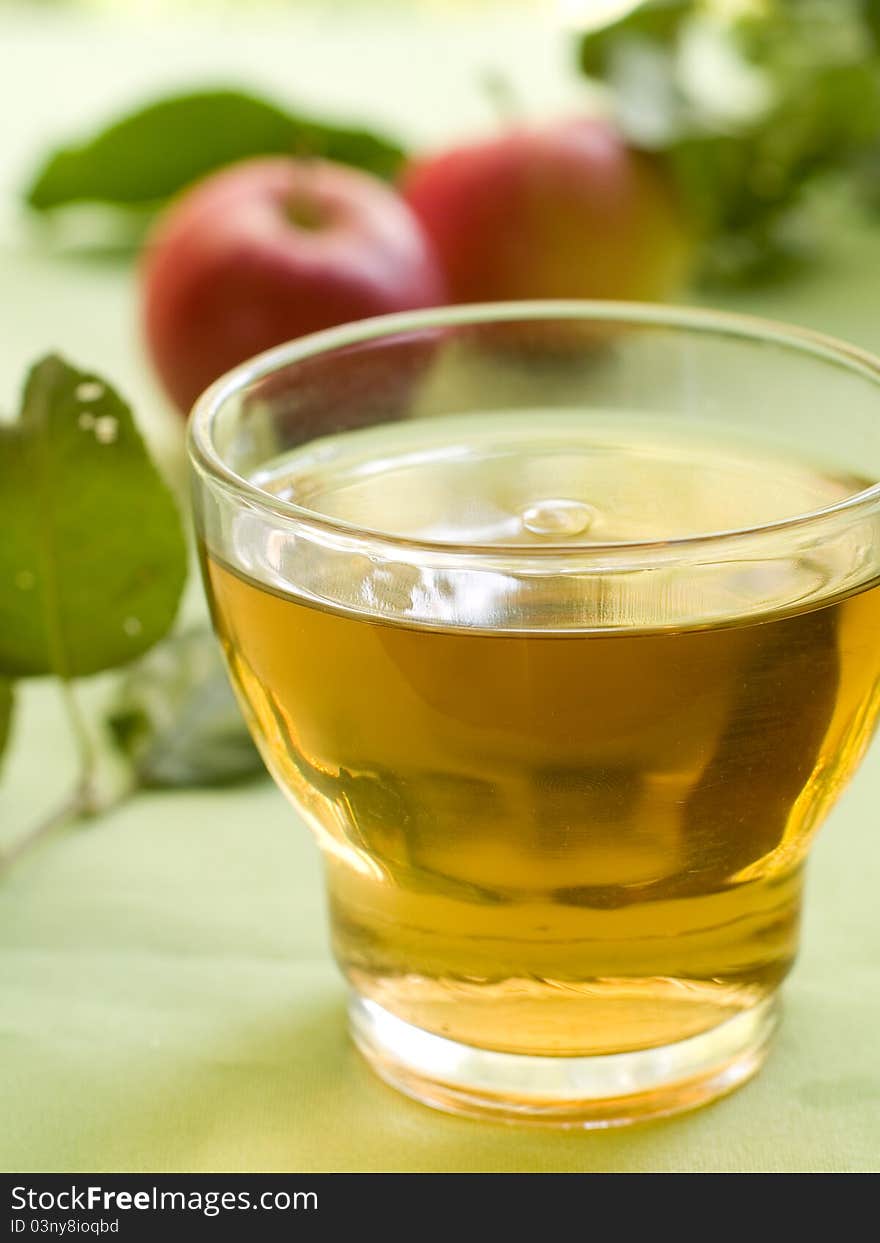 Glasses of apple juice with apples on the background.