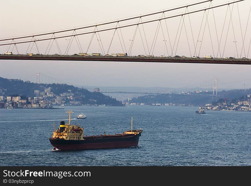 The Bosporus Bridge whcih spans the Bosphorous. Industrial ship passing through straits of Bosphorus... Bosporus Bridge behind, Rumeli Fortress and Fatih Sultan Mehmet Bridge. The Bosporus Bridge whcih spans the Bosphorous. Industrial ship passing through straits of Bosphorus... Bosporus Bridge behind, Rumeli Fortress and Fatih Sultan Mehmet Bridge...