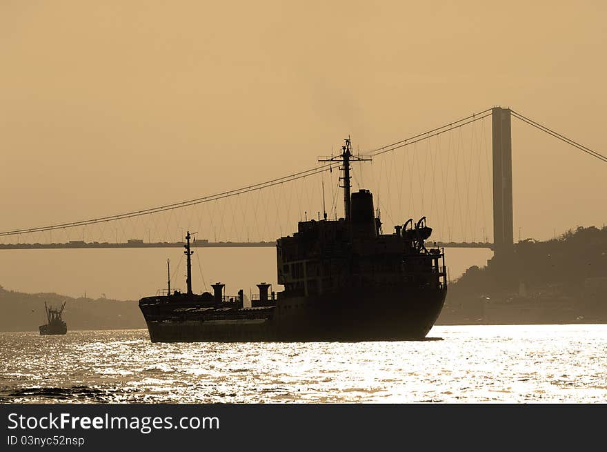 The Bosporus Bridge whcih spans the Bosphorous. Industrial ship passing through straits of Bosphorus. The Bosporus Bridge whcih spans the Bosphorous. Industrial ship passing through straits of Bosphorus..