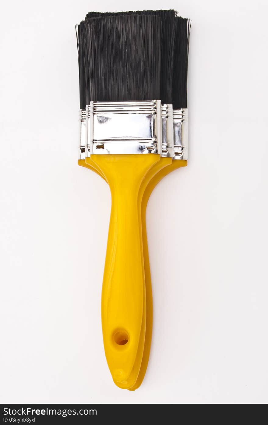 Three new yellow paint brushes stacked on top of each other on a white background. Three new yellow paint brushes stacked on top of each other on a white background