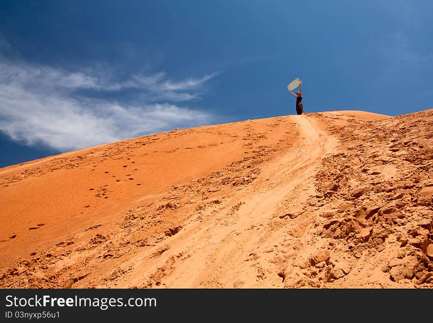 Woman standing on top of the sand dunne, with slideboard in her hands. Mui Ne - Vietnam (Red dunnes). Woman standing on top of the sand dunne, with slideboard in her hands. Mui Ne - Vietnam (Red dunnes)