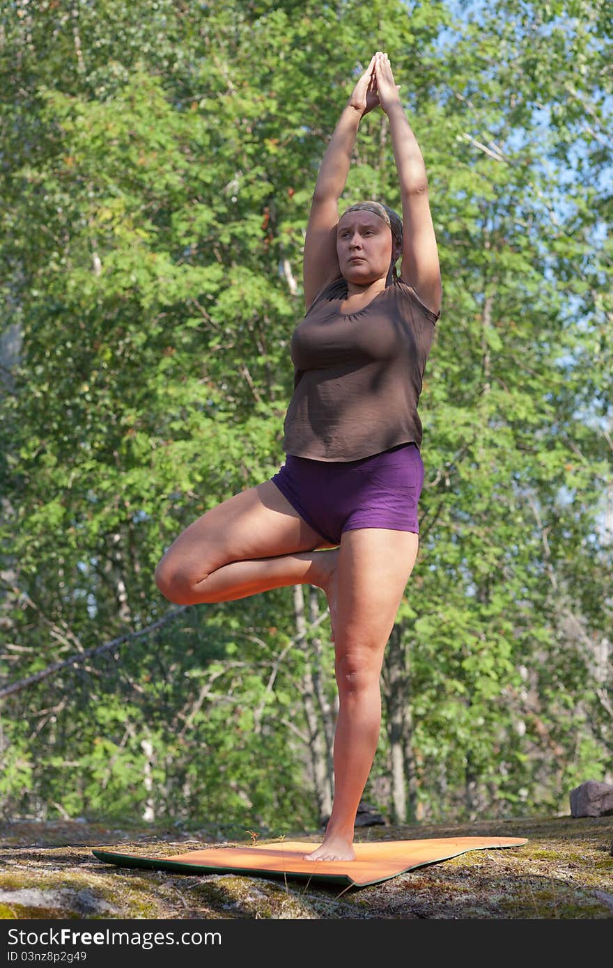 The woman trains yoga in wood. A pose vrikshasana. The woman trains yoga in wood. A pose vrikshasana