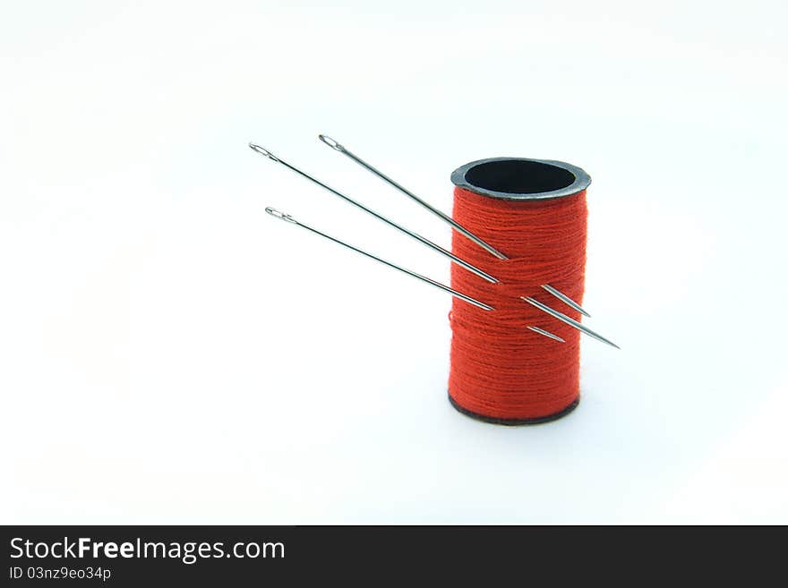 Three sharp metal needles in the bobbin with red thread. Three sharp metal needles in the bobbin with red thread