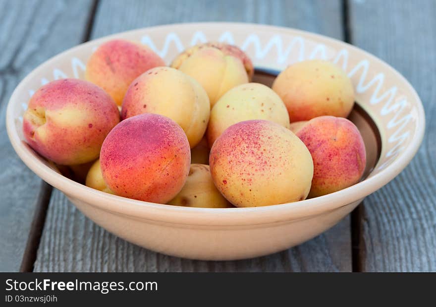 Apricots on the plate on a wooden table. Apricots on the plate on a wooden table.