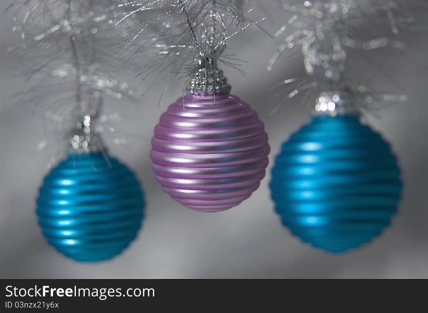 Three metallic Christmas ornaments hanging on tree