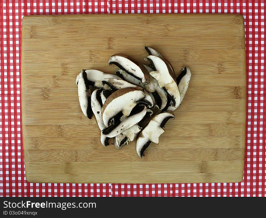 Fresh Sliced Portabella Mushrooms on Clean Cutting Board isolated on red and white checkered background. Fresh Sliced Portabella Mushrooms on Clean Cutting Board isolated on red and white checkered background