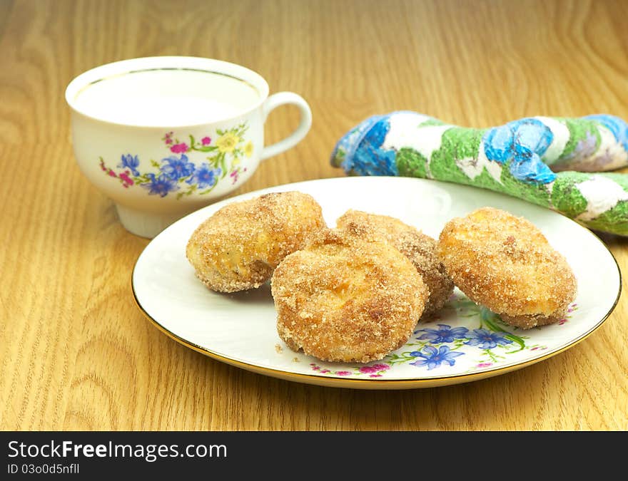 Close up image of a plate of delicious homemade nutmeg muffins rolled in cinnamon sugar with a cup of milk. Close up image of a plate of delicious homemade nutmeg muffins rolled in cinnamon sugar with a cup of milk.