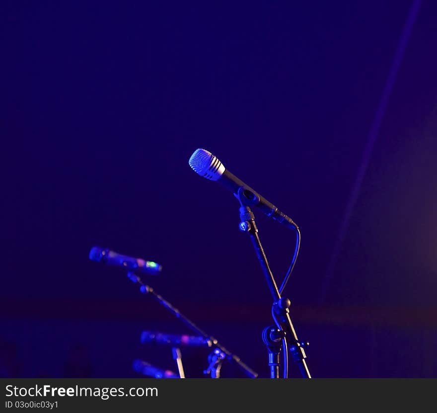 A row of microphones on a concert scene in blue spotlight