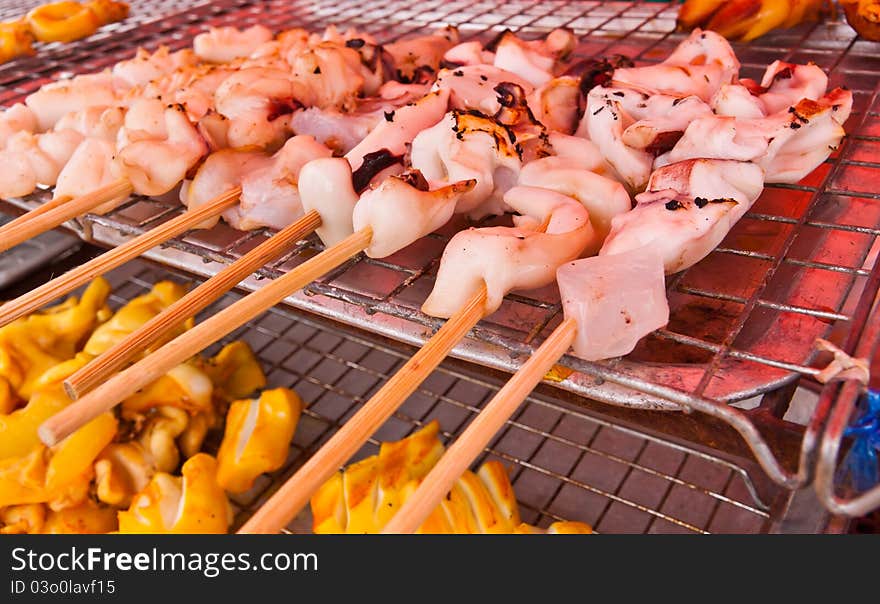 Grilled squids in group with wooden stick on grill. Grilled squids in group with wooden stick on grill