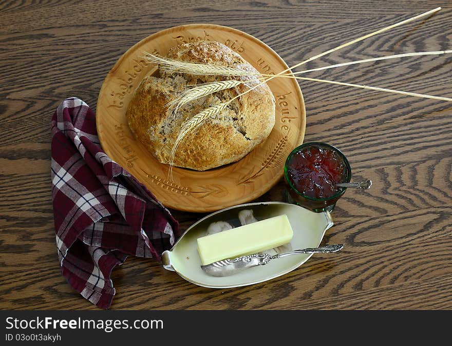 Whole wheat bread on wooden German plate with butter on vintage butter dish and jelly in vintage jelly dish.