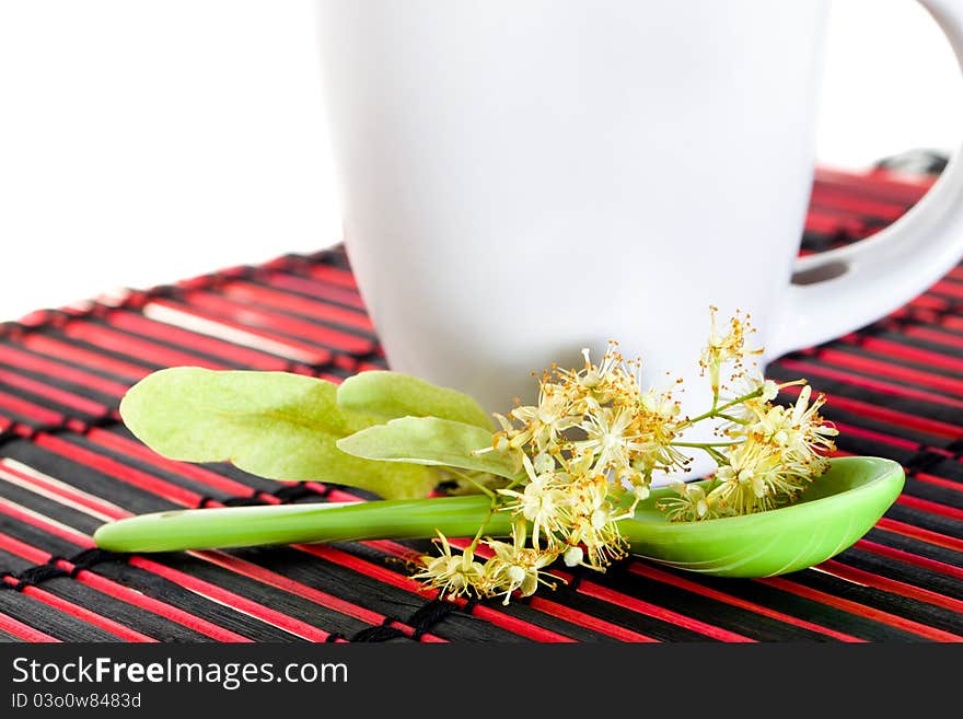 The flower of a linden lying in a green spoon about cup (isolated). The flower of a linden lying in a green spoon about cup (isolated)