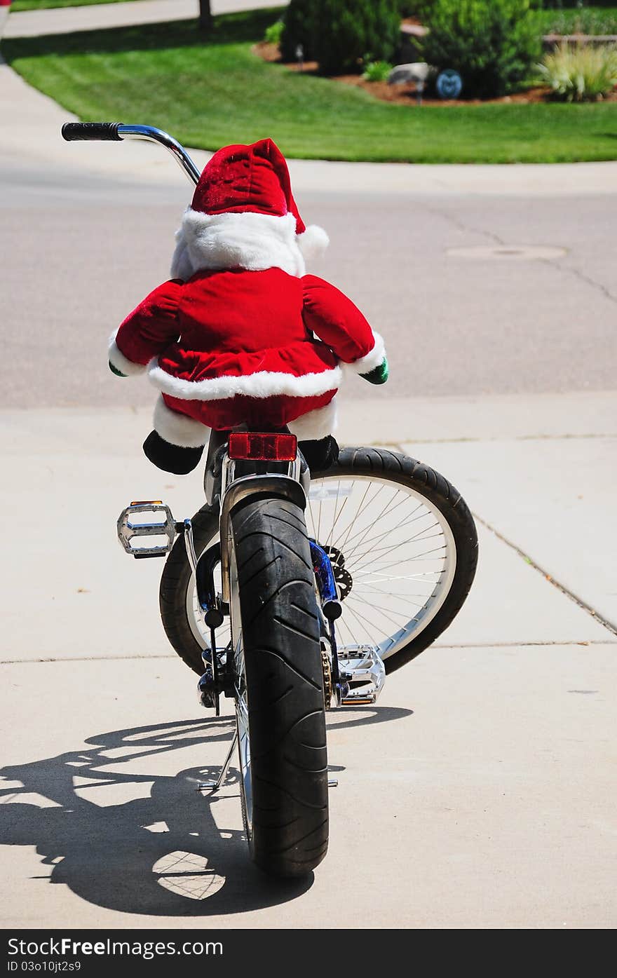 Santa Clause during the off season cruising on his chopper style bicycle. Stuffed Santa doll sitting on a bicycle. Santa Clause during the off season cruising on his chopper style bicycle. Stuffed Santa doll sitting on a bicycle.