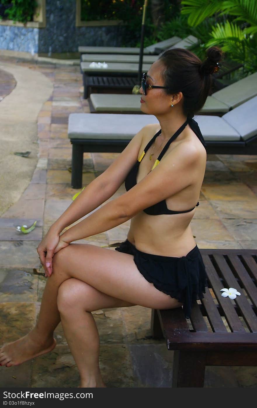 Woman in black bikini sitting on bank