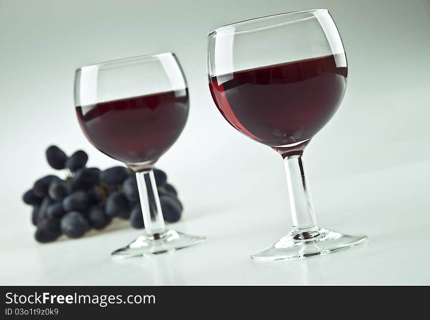 Two glasses of red wine and some grapes. Two glasses of red wine and some grapes