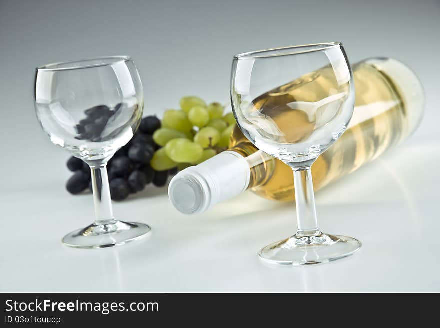 Bottle of white wine and two empty glasses. Bottle of white wine and two empty glasses