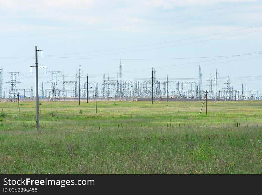 Transformation station and power lines on green field in Russia