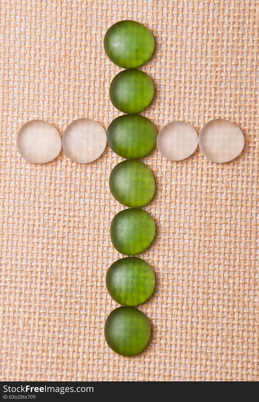 Glass crucifix on a straw background.