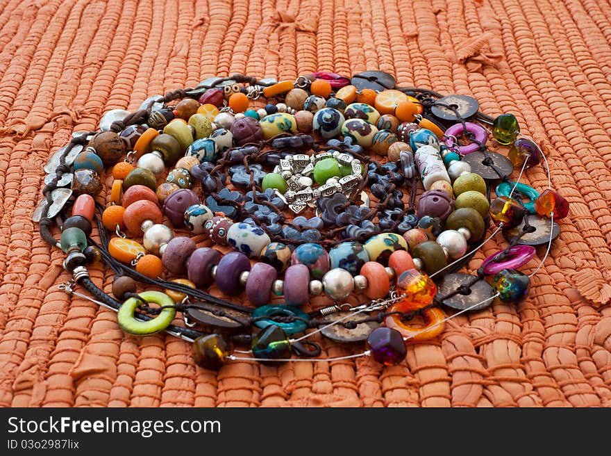 Handmade varicoloured beads in a spiral on a orange background