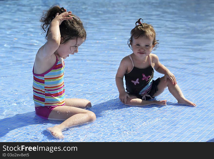 Two small girls are playing in the swimming pool