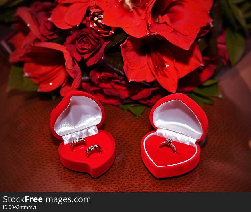 ROM/Wedding rings displayed on a table with red roses behind. ROM/Wedding rings displayed on a table with red roses behind.