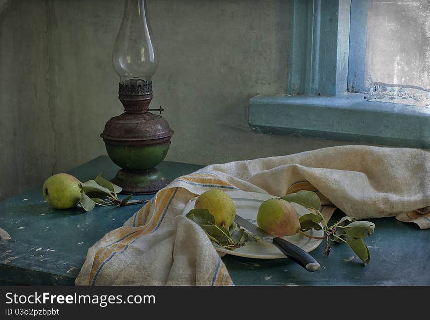 Three pears and kerosene lamp on a table