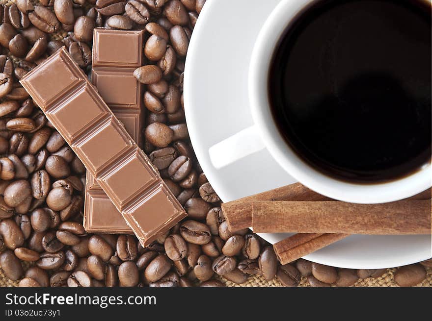 Coffee beans with cinnamon sticks and cup of coffee