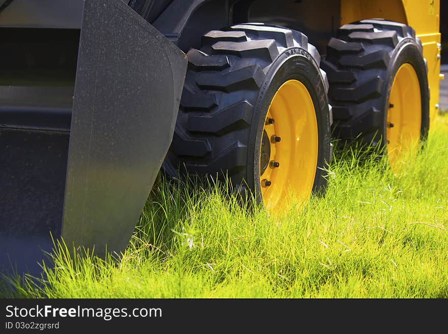 Big yellow black tractor wheels on green grass