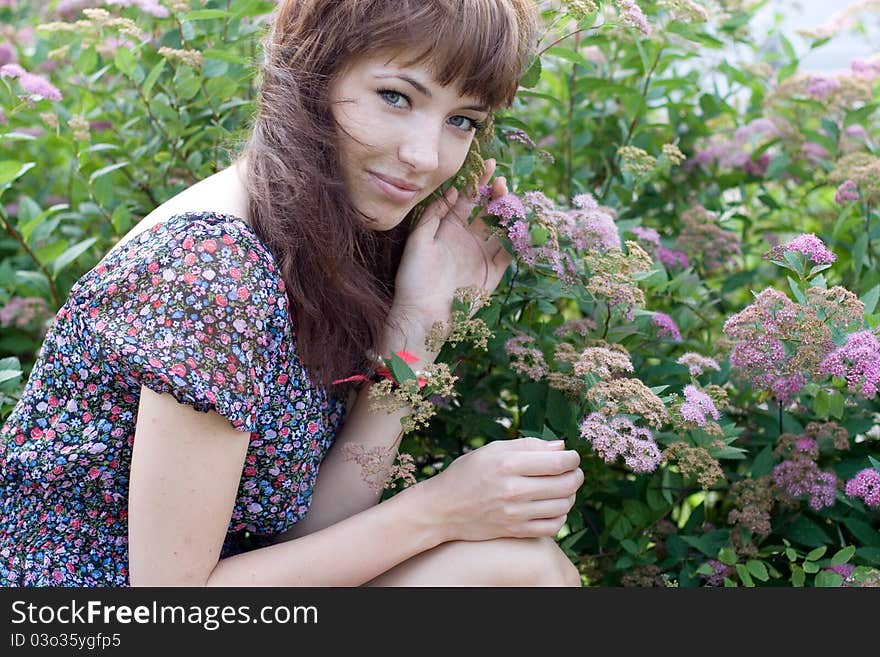 Beautiful girl sitting on meadow with flowers