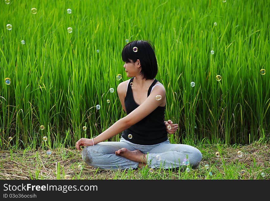 Girl practicing yoga, sitting in paddy field. Girl practicing yoga, sitting in paddy field