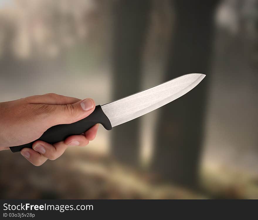 Hand holding knive - in a background dark wood. Hand holding knive - in a background dark wood