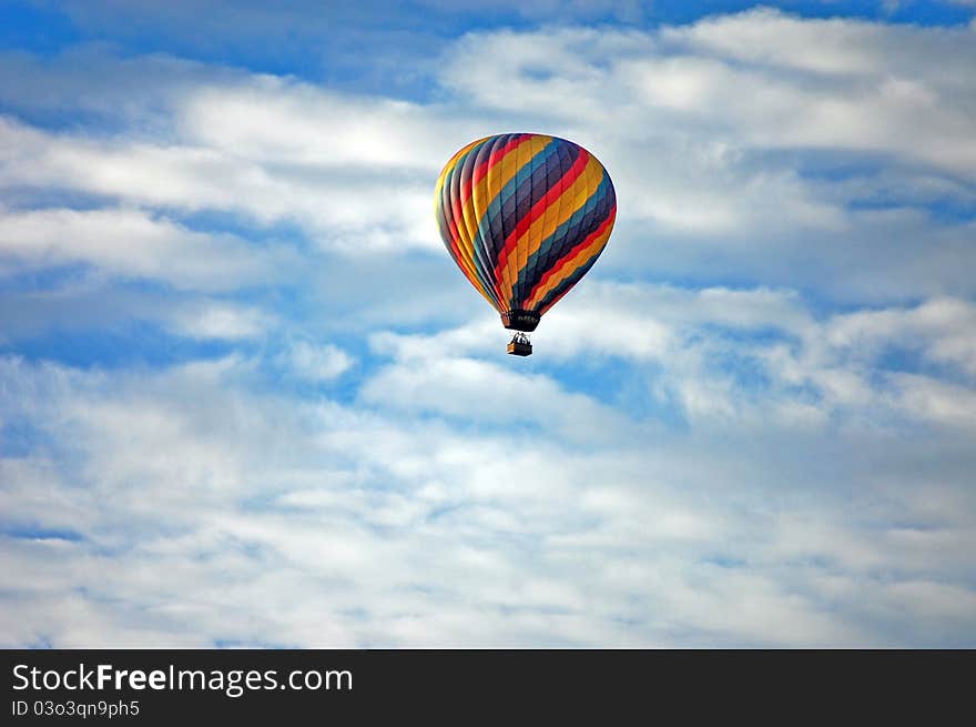 A colorful hot air balloon on a backdrop of white clouds and blue sky. A colorful hot air balloon on a backdrop of white clouds and blue sky