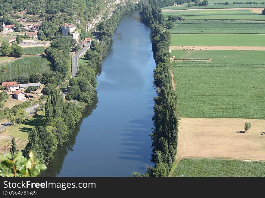 On the left is Cadrieu - a village situated near the river Lot in the Lot department Midi-Pyrénées region of France). You can see the remains of the medieval Knights Templar Castle castle. The fields on the right across the river located in Saujac, a commune in the Aveyron department in southern France. On the left is Cadrieu - a village situated near the river Lot in the Lot department Midi-Pyrénées region of France). You can see the remains of the medieval Knights Templar Castle castle. The fields on the right across the river located in Saujac, a commune in the Aveyron department in southern France.