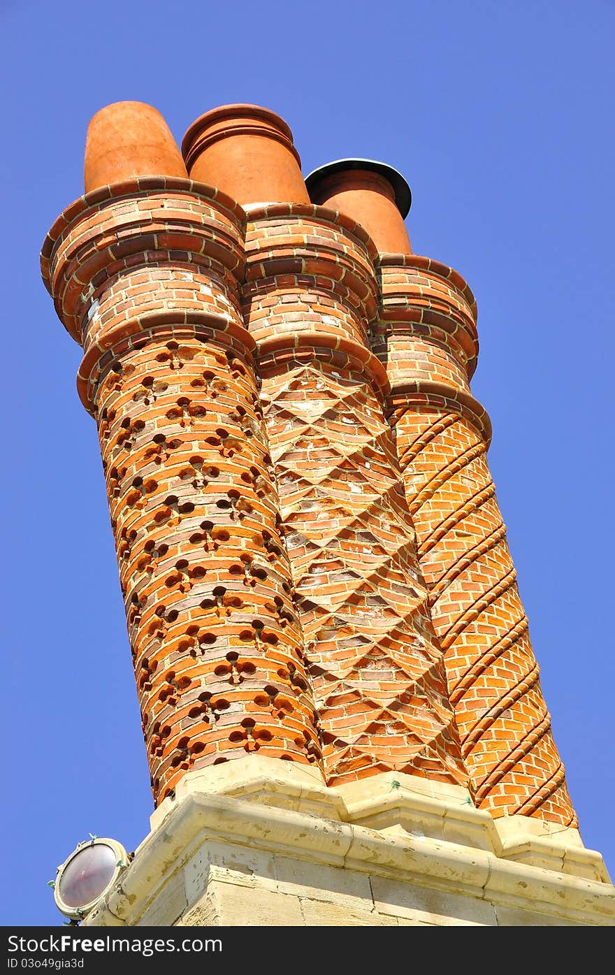 Three decorative chimneys on the top of a graystone mansion.