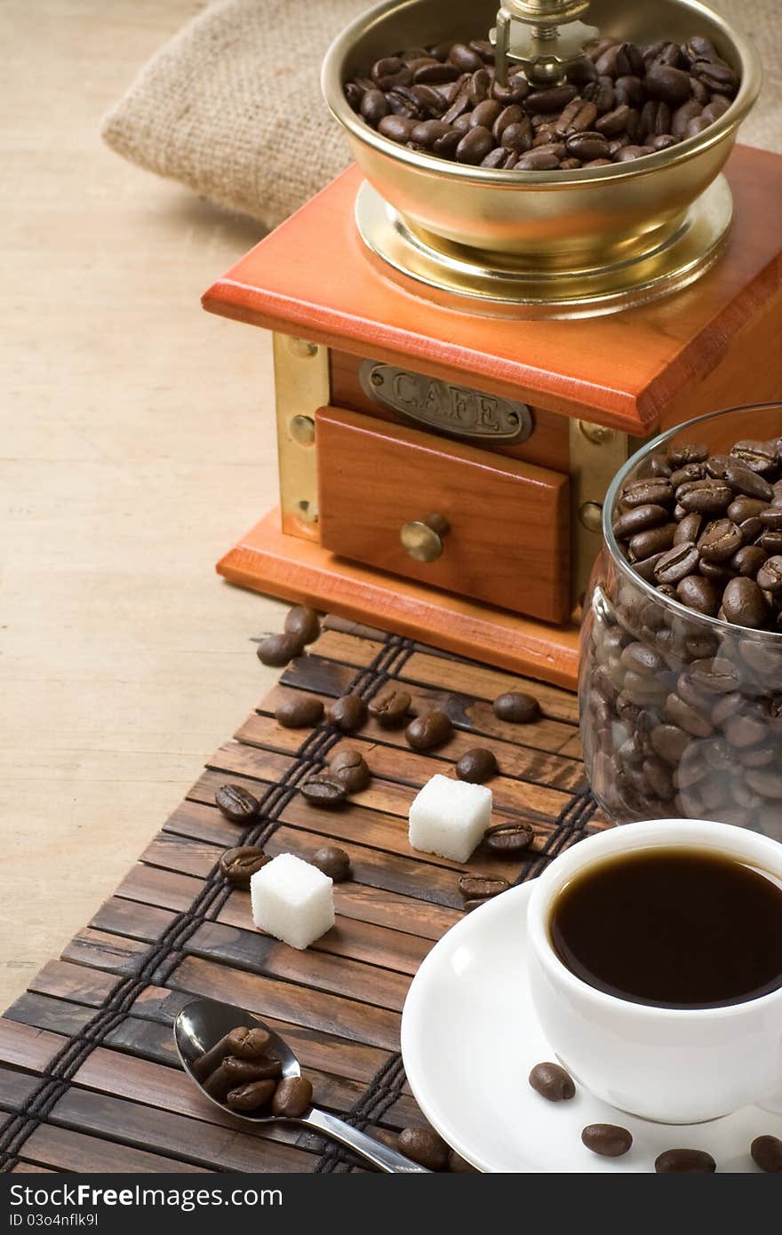 Cup of coffee and grinder with roasted beans on wooden. Cup of coffee and grinder with roasted beans on wooden