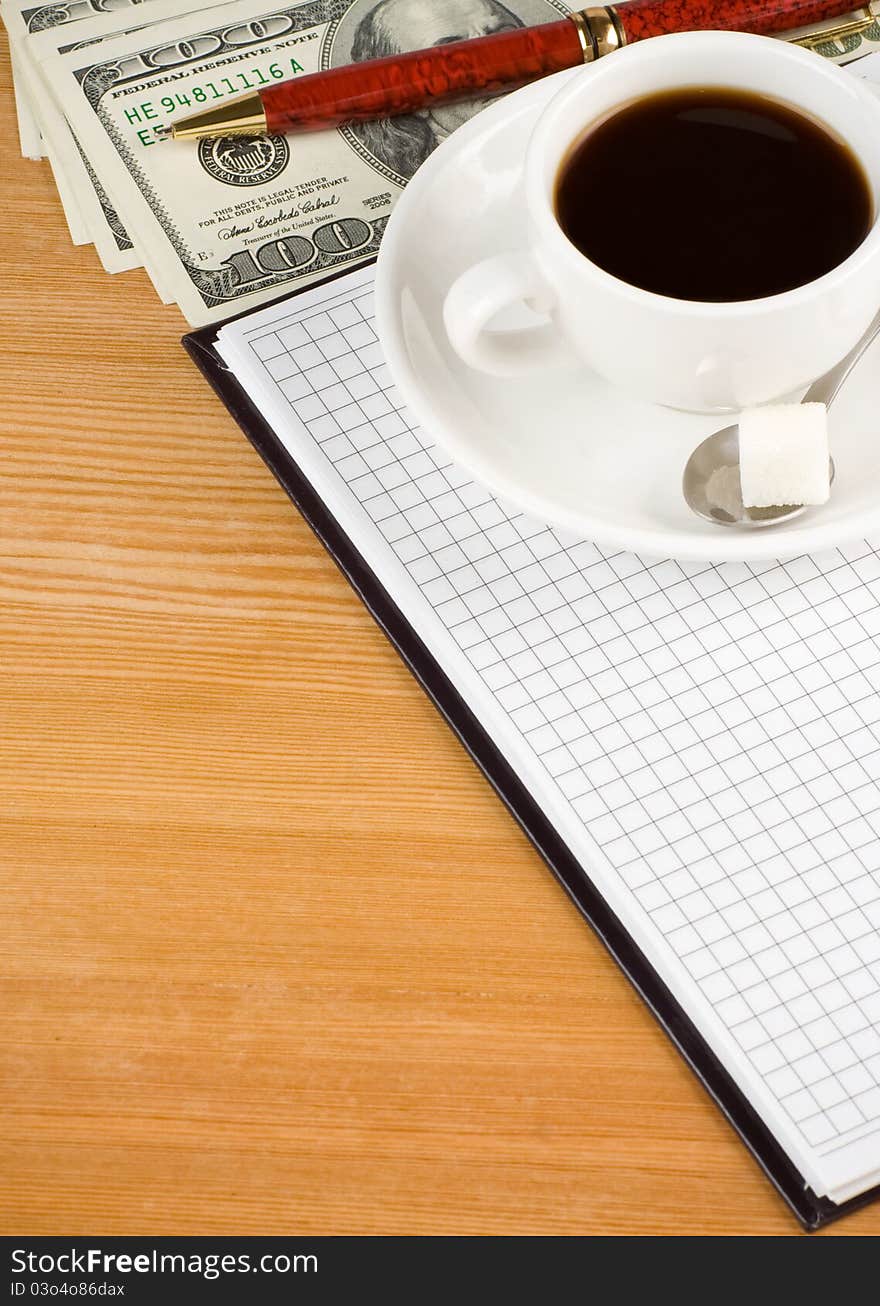 Cup of coffee and notebook with dollar on wood table