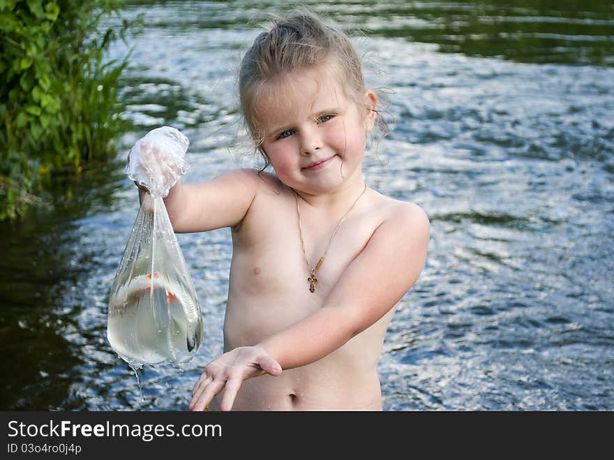 The child on the nature holds in hands fish which has caught in the river. The child on the nature holds in hands fish which has caught in the river