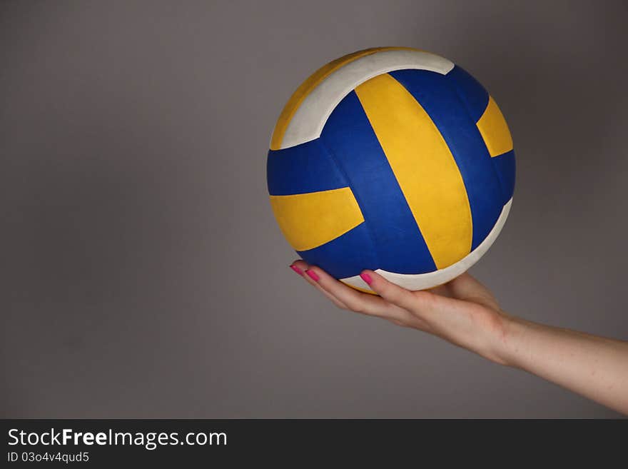 Yellow and dark blue ball in a hand on a gray background