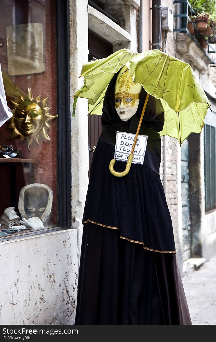 Doll in Venetian costume in front of a store