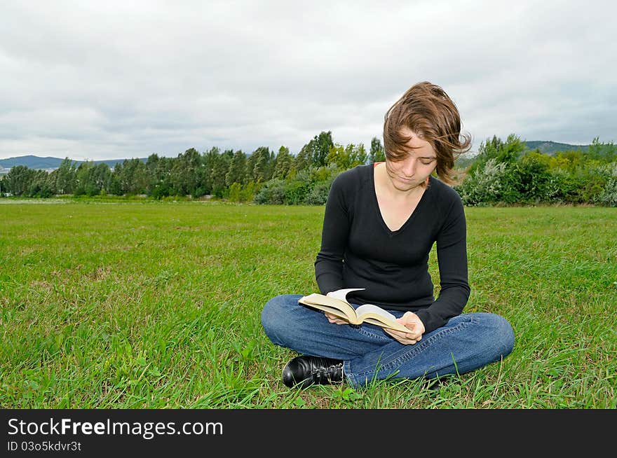 Young woman reading a book on the green grass. Young woman reading a book on the green grass