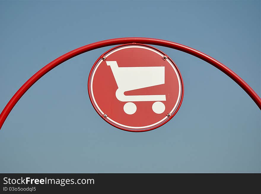 Red shopping cart sign with blue sky background