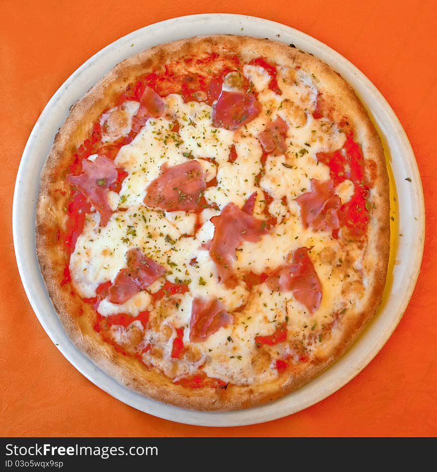 Italian pizza with ham and Mozzarella on orange tablecloth