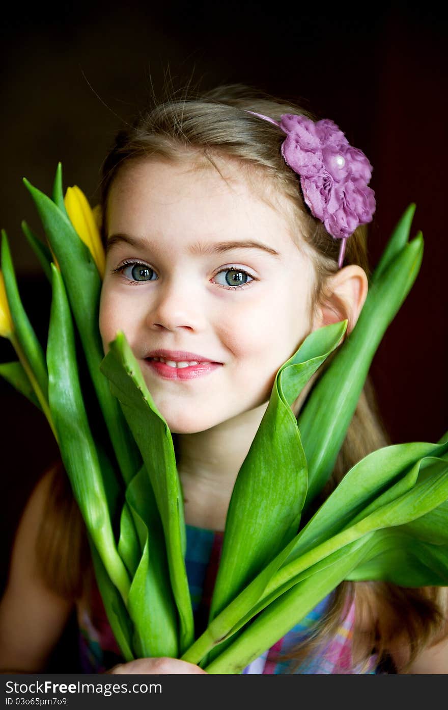 Portrait of adorable sunny child girl with tulips