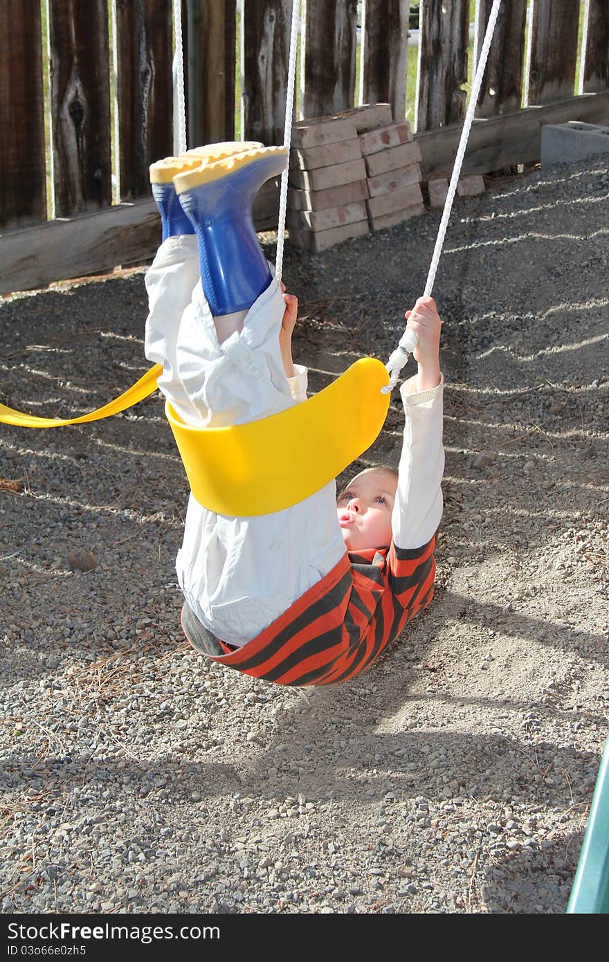 Young blond boy playing outdoors on swing set. Young blond boy playing outdoors on swing set