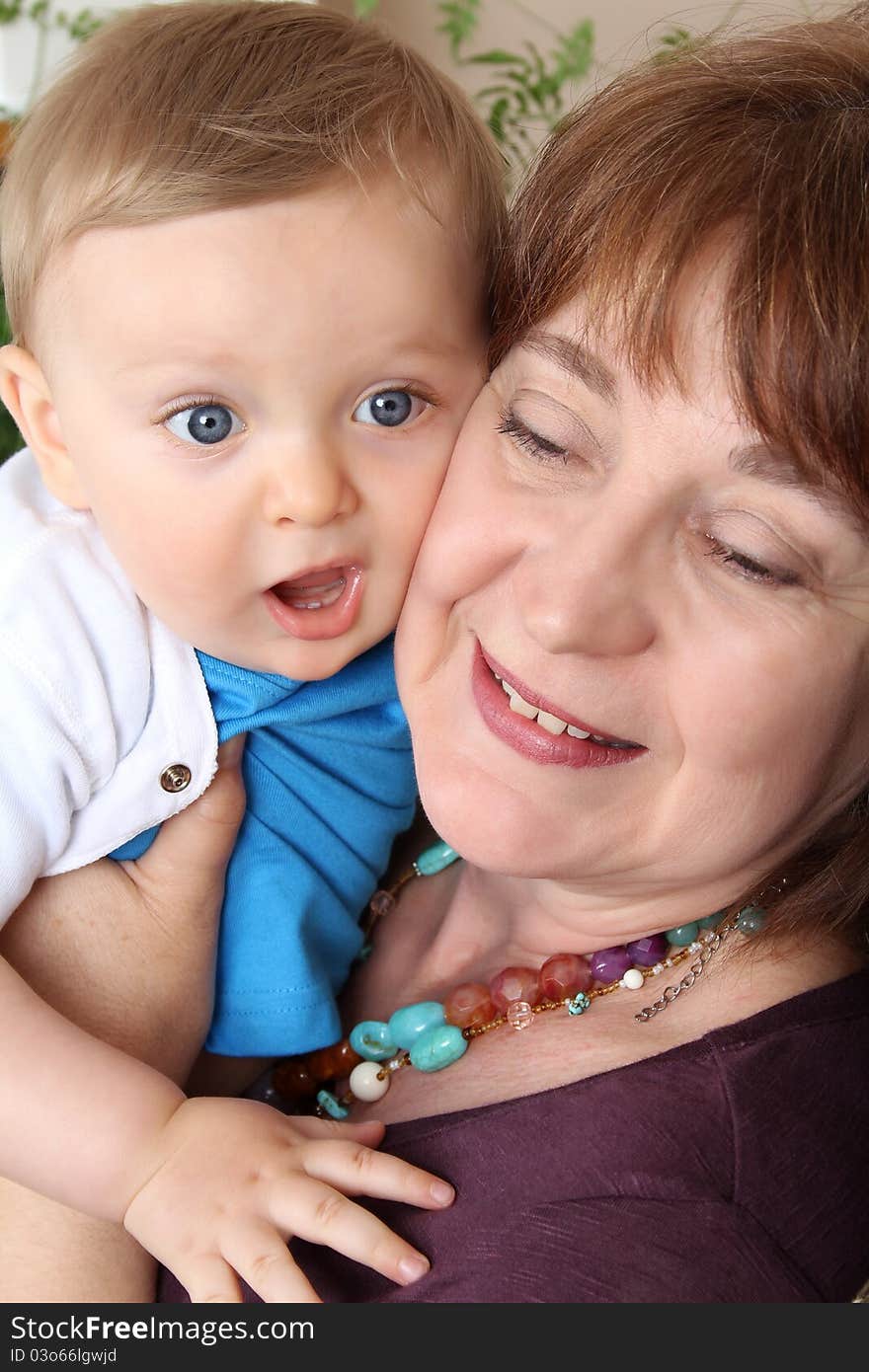 Beautiful blond baby boy sitting by his grandmother. Beautiful blond baby boy sitting by his grandmother