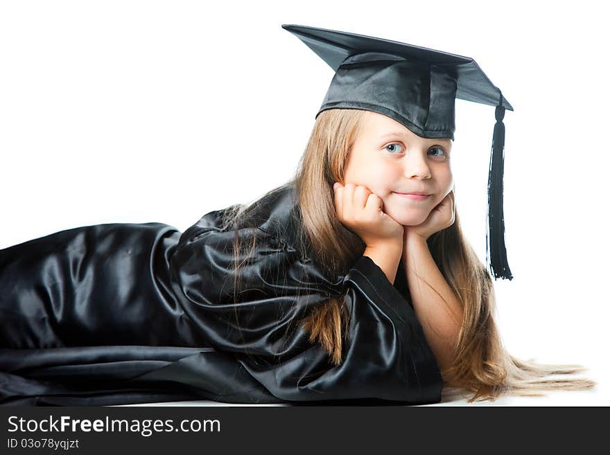 Portrait of smiling cute girl in black academic cap and gown lying on isolated white. Portrait of smiling cute girl in black academic cap and gown lying on isolated white